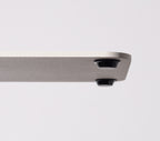A close-up of the corner of a white Gather 2x2 Base Plate shows two small black cylindrical feet underneath. Made from powder coated steel, it rests on a plain white background.
