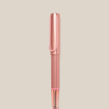 The LAMY AL-star Rollerball (Flamingo) features a pink anodized aluminum body, clear grip, and black ink tip, shown vertically on a light beige background for smooth writing.