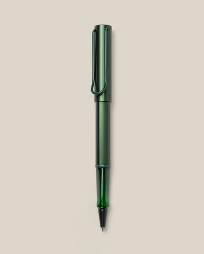 A LAMY AL-star Rollerball (Pine) pen in green metallic, with matching cap and clip, is displayed vertically on a plain light beige background. This refillable pen ensures smooth, effortless writing.