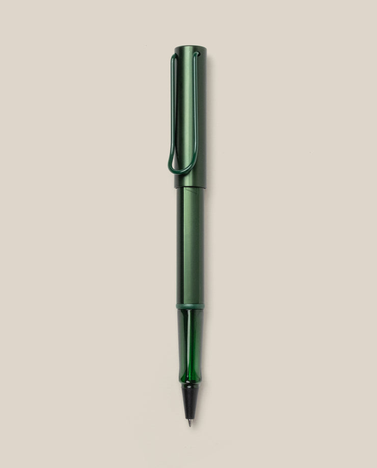 A LAMY AL-star Rollerball (Pine) pen in green metallic, with matching cap and clip, is displayed vertically on a plain light beige background. This refillable pen ensures smooth, effortless writing.