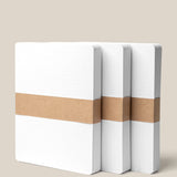 Three Analog Dot Grid Cards - Large (3-Pack), featuring white, square-edged covers and brown paper bands, stand upright on a beige background. Made from premium card stock, they're perfect for note taking. A corner label reads "Large - 5” x 6.5”.