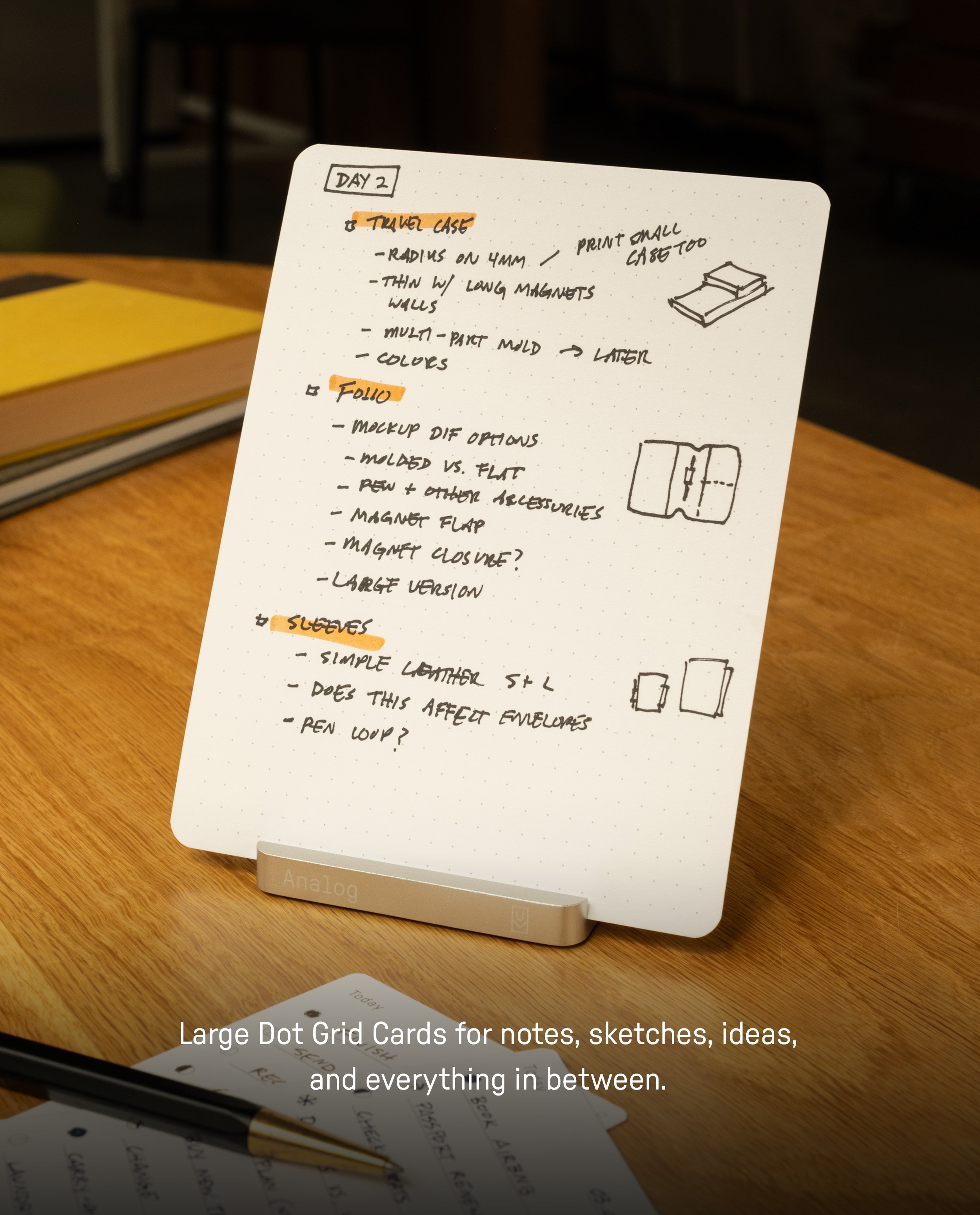 A Large Dot Grid Card from the Analog Starter Kit - BOGO Special, featuring handwritten notes, bulleted lists, and sketches under the title “Day 2,” is displayed upright on a stand atop a wooden table. Text below reads: Large Dot Grid Cards for notes, sketches, ideas—perfect for any paper card system or task cards.