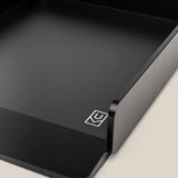 A close-up of the Analog Capture Kit - Large (Black Aluminum): a minimalist aluminum card tray with angular corners and a white geometric logo, on a light beige background—ideal for organizing large dot grid cards.