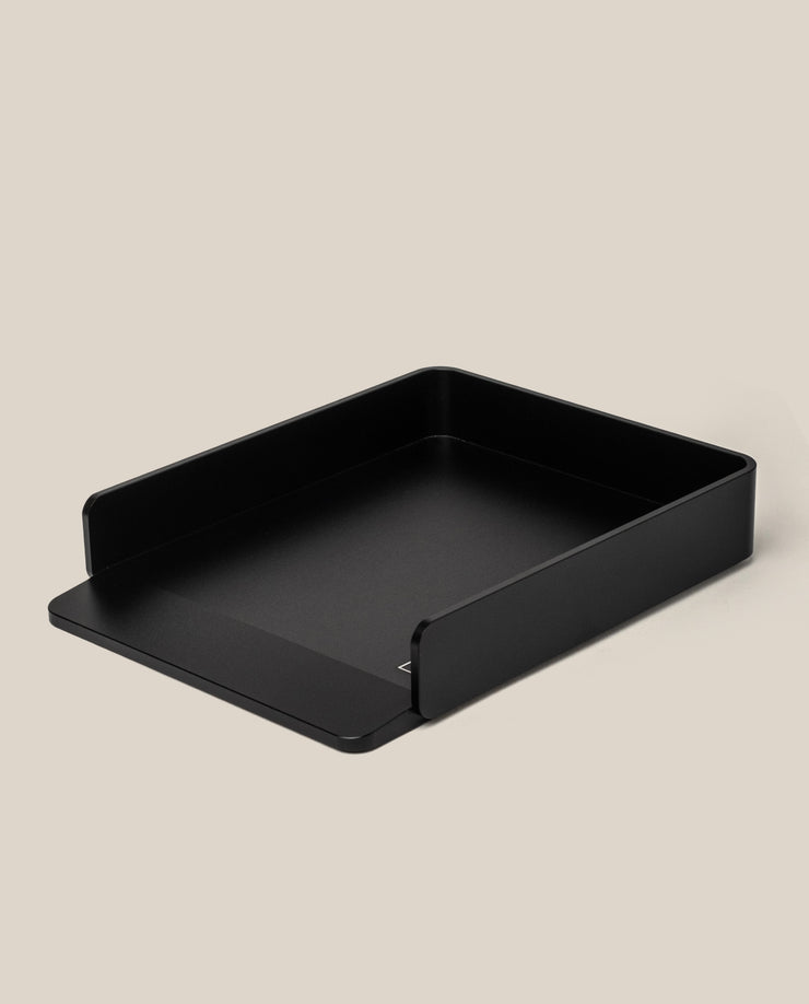 A black, rectangular aluminum card tray with low sides and a front cutout sits on a beige background—ideal for organizing large dot grid cards from the Analog Capture Kit - Large (Black Aluminum).