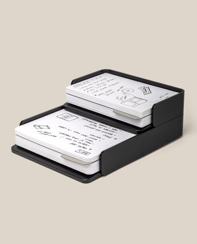 The Analog Capture Kit - Small & Large (Black Aluminum) holds two stacks of Dot Grid Cards filled with handwritten notes, diagrams, and sketches, all displayed against a plain beige background.