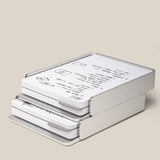 A stack of Analog Capture Kit - 2 Large (Silver Aluminum) trays holds neatly arranged paper with diagrams and text on a light beige background, showcasing a minimalist, modern design and an elegant silver aluminum card tray.