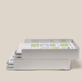 The Analog Capture Kit - 2 Large (Silver Aluminum) is a silver, two-tiered card tray that organizes paper, dot grid cards, and documents with sketches and green highlights, displayed on a neutral beige background.