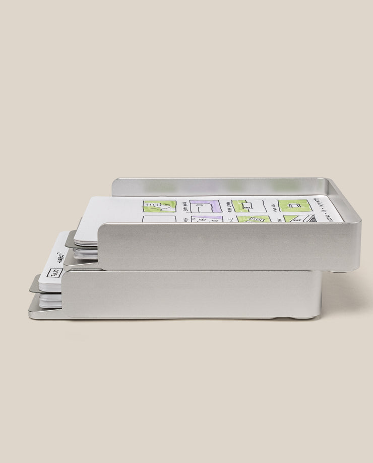 The Analog Capture Kit - 2 Large (Silver Aluminum) is a silver, two-tiered card tray that organizes paper, dot grid cards, and documents with sketches and green highlights, displayed on a neutral beige background.
