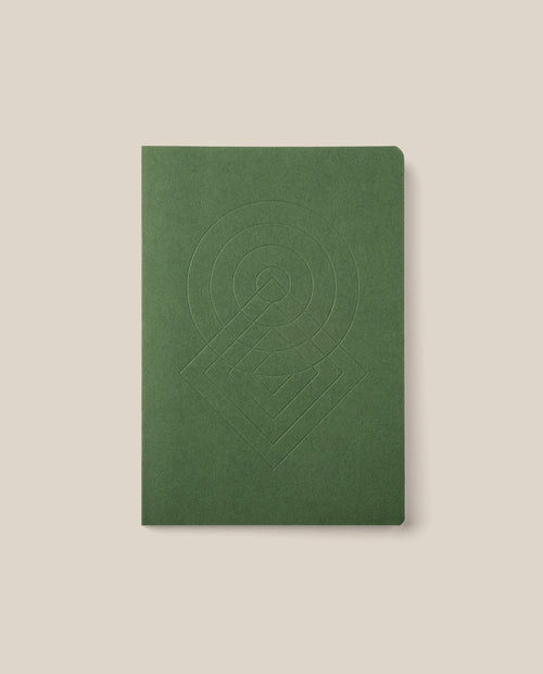 The Layflat Notebook (Green), featuring a geometric embossed design on its cover, rounded corners, and a green dot grid layout, is centered on a light beige background.