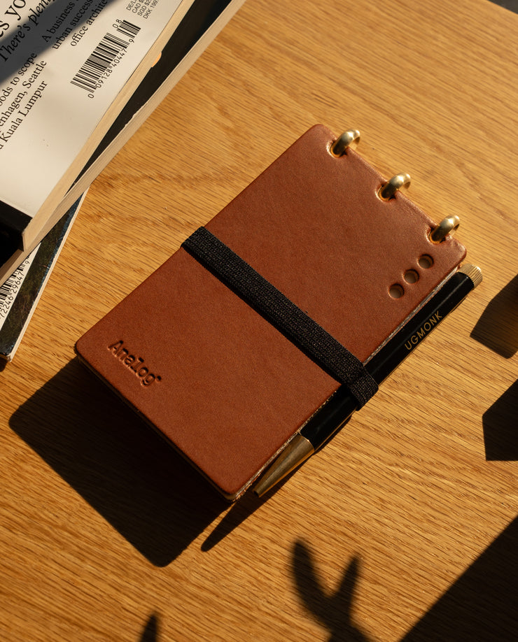 Brown notebook with a pen on a wooden surface
