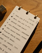 Notebook with handwritten to-do list on a wooden surface