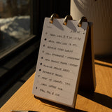 Flip chart with a to-do list on a wooden surface with a pen next to it