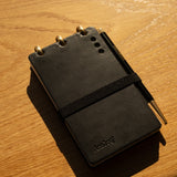 Black leather notebook with gold accents on a wooden surface