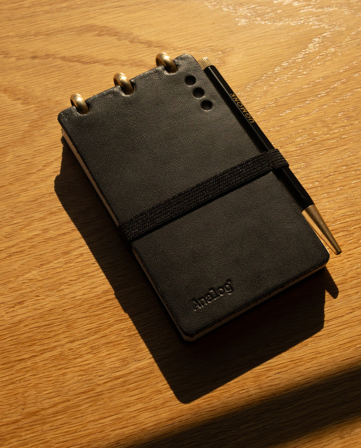 Black leather notebook with gold accents on a wooden surface