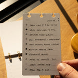 Hand holding a to-do list card with tasks on a wooden surface