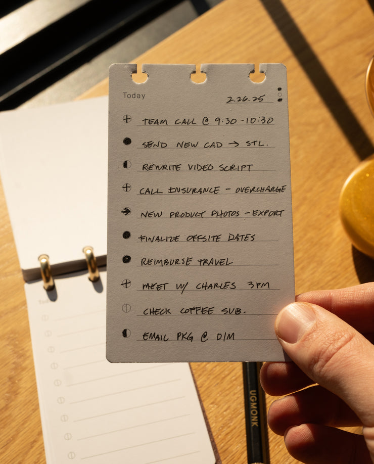 Hand holding a to-do list card with tasks on a wooden surface