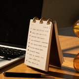Desk with a notepad, pen, and laptop on a wooden surface