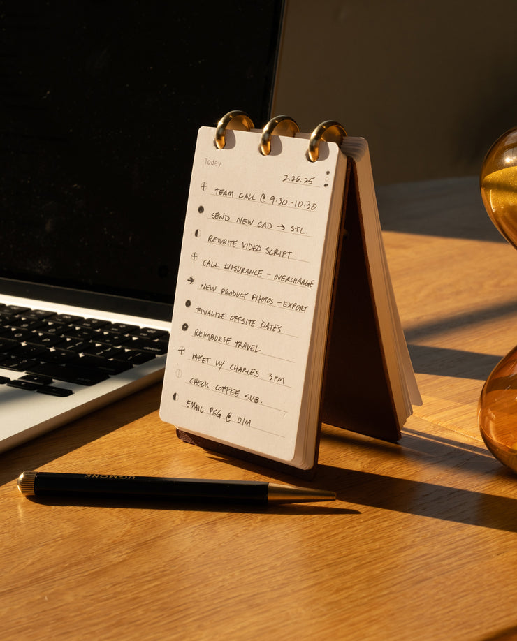 Desk with a notepad, pen, and laptop on a wooden surface