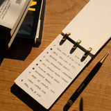 Notebook with a to-do list on a wooden surface with a pen next to it
