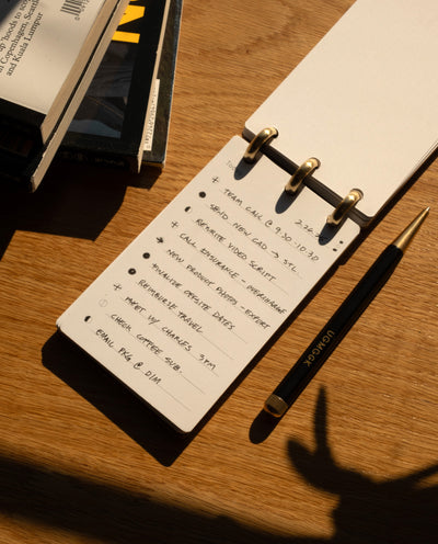 Notebook with a to-do list on a wooden surface with a pen next to it
