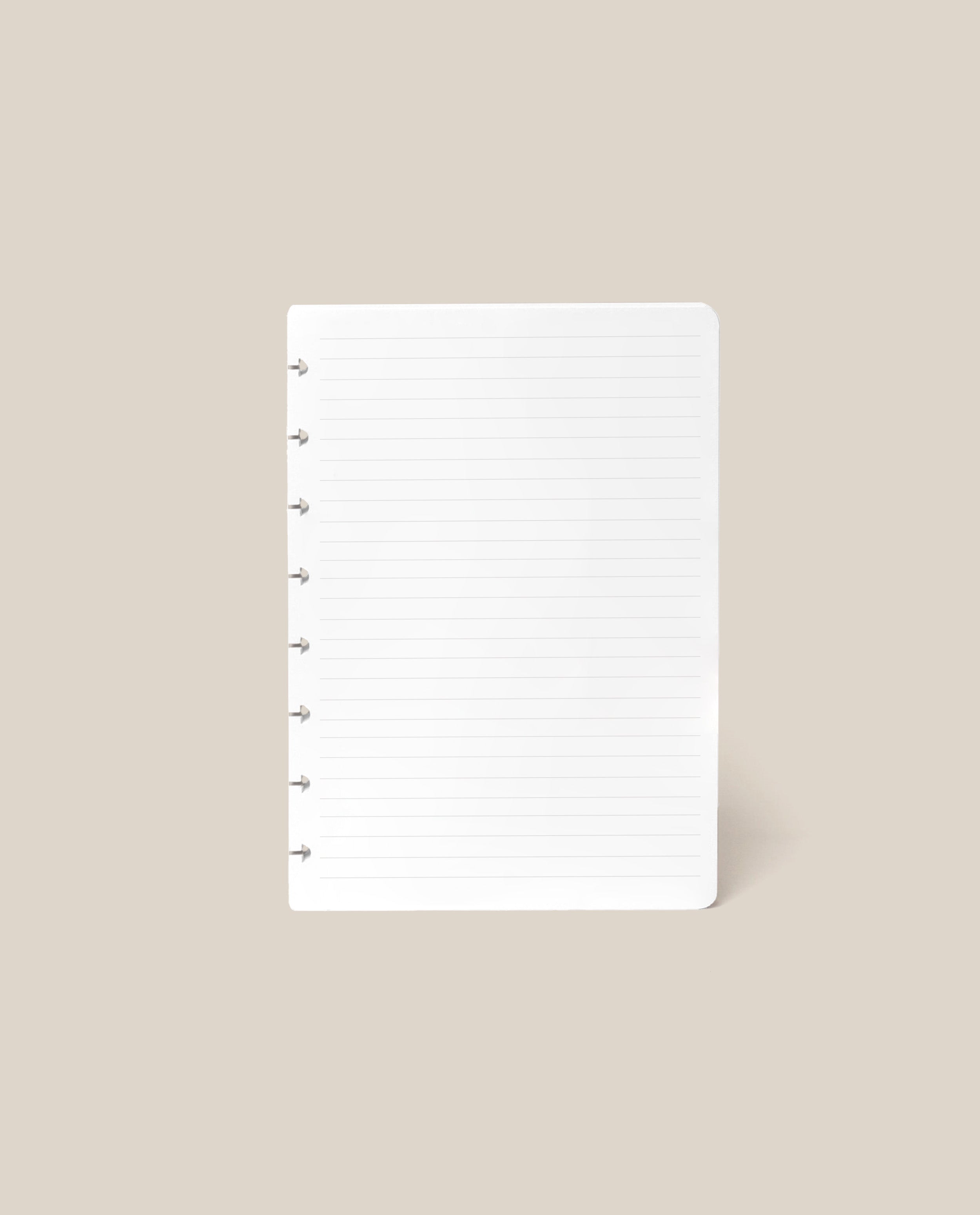 A Discbound Journal Refill - Lined (Standard 6″ x 8.5″) page, featuring a clean white surface with ruled lines and punched holes on the left, is centered against a plain beige background—ideal for adding to your Heirloom Discbound Journal.
