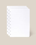 Four overlapping sheets of the Discbound Journal Refill - Lined (Standard 6″ x 8.5″)—white, lined pages with holes along the left edge, perfect for your Heirloom Discbound Journal—set against a plain beige background.