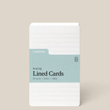 A stack of Analog Lined Cards - Small, in white 3x5 with a blue-green label, 50 cards made from 100lb uncoated cardstock, displayed upright on a beige background.