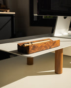 A Magnet Kit, featuring a pen tray and Analog Weekly, rests on a minimalist white desk with wooden legs, illuminated by sunlight near a computer monitor and the sleek Gather Monitor Stand.