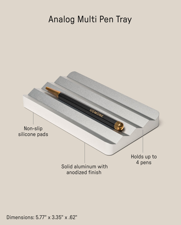 The Analog Multi Pen Tray (Silver Aluminum) features a solid anodized aluminum build, non-slip silicone pads, and holds up to 4 pens. Dimensions: 5.77" x 3.35" x 0.62". Shown with one black and gold pen resting on the tray.