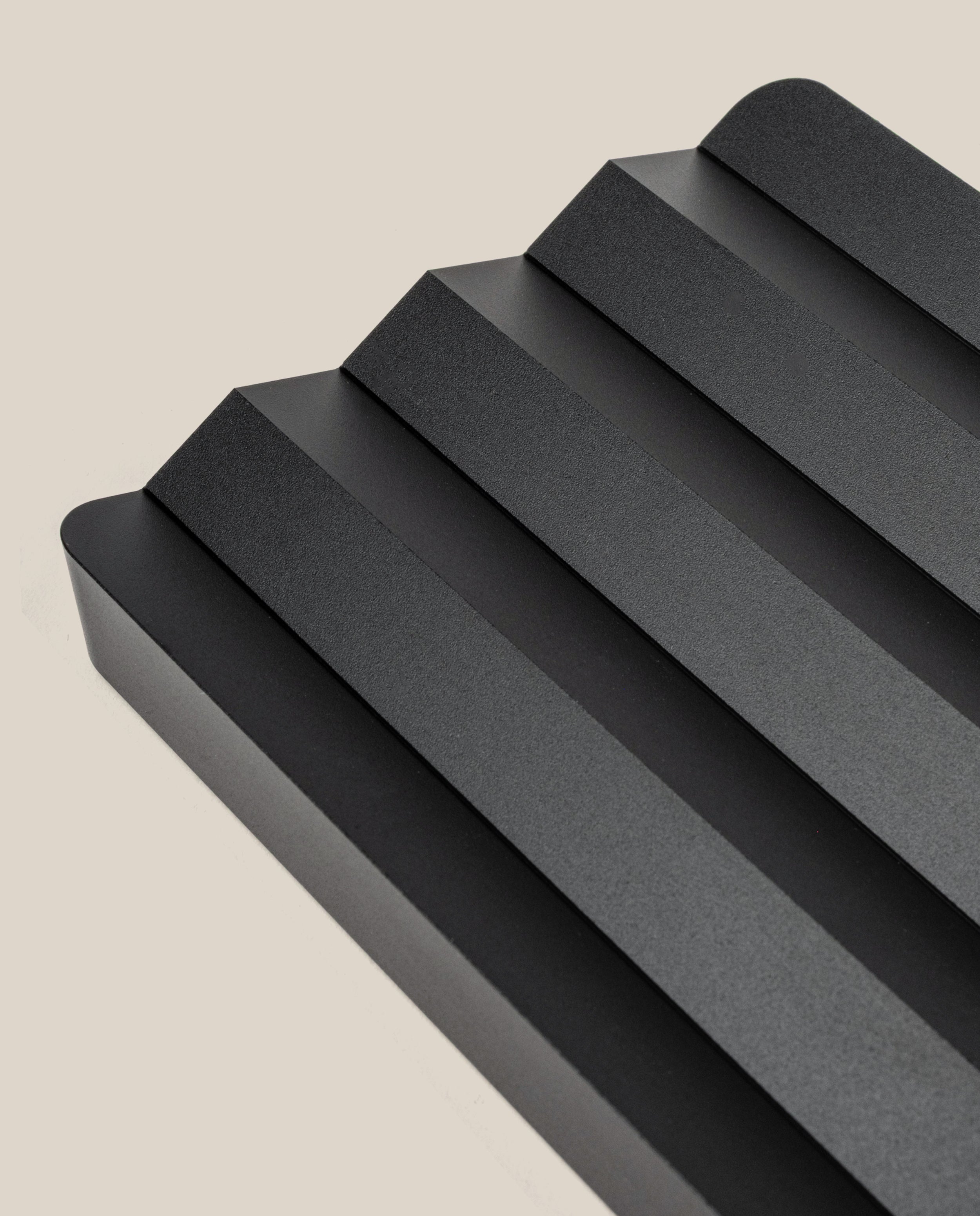The Complete Analog Collection (Black Aluminum) features a sleek, minimalist tray with four angled grooves and rounded edges, photographed on a light beige background—a modern geometric desktop organizer.