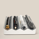 The Complete Analog Collection (Silver Aluminum) desktop organizer, shown on a light beige background, holds four writing tools: a black and gold pencil, a black pen, a translucent mechanical pencil, and a gray pen.