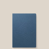 A closed Layflat Notebook (Navy) with an embossed geometric diamond cover and Smyth sewn binding is shown on a plain light beige background.