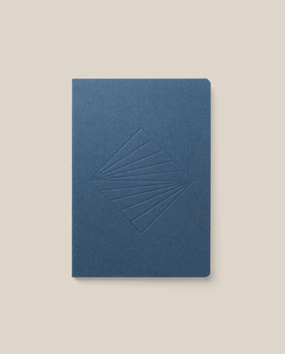 A closed Layflat Notebook (Navy) with an embossed geometric diamond cover and Smyth sewn binding is shown on a plain light beige background.