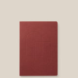 A maroon Layflat Notebook with rounded corners and an embossed geometric cover design, displayed on a light beige background.