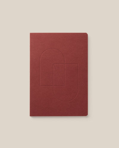 A maroon Layflat Notebook with rounded corners and an embossed geometric cover design, displayed on a light beige background.