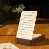 The Analog Daily Focus Kit (Walnut) rests on a wooden table beside a pencil and task cards, with sunlight casting warm shadows that accentuate this simple yet effective productivity system.