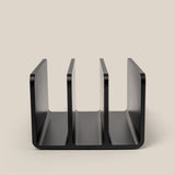 A black, three-slot desktop organizer from The Complete Analog Collection (Black Aluminum) stands upright on a beige surface, photographed from the front to display its U-shaped, open compartments.