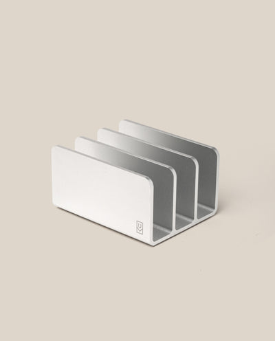 The Analog Card Organizer (Silver Aluminum) features three minimalist slots, ideal for storing cards or organizing mail, files, and devices. Shown on a plain beige surface.