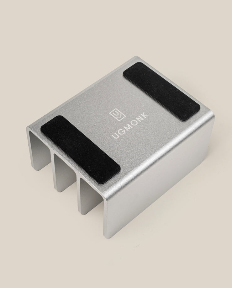 The Complete Analog Collection (Silver Aluminum) desktop organizer features three slots, two black non-slip pads, and the UGMONK logo on its surface, shown against a beige background.