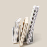 Three The Complete Analog Collection (Silver Aluminum) desktop organizers hold varying stacks of paper upright against a light beige background; each stack differs in height and thickness.