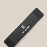 The Analog Pen Tray (Black Aluminum) is a sleek, rectangular aluminum organizer with rounded corners, black pads on both ends, and features the Ugmonk logo and text in white. It rests on a light beige surface.