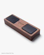 Introducing the Magnet Kit (Pen Tray and Analog Weekly): a wooden pen tray featuring two black rectangular pads on the bottom and a central UGMONK label. Subtle magnets keep your writing essentials neatly organized, all showcased against a white background.