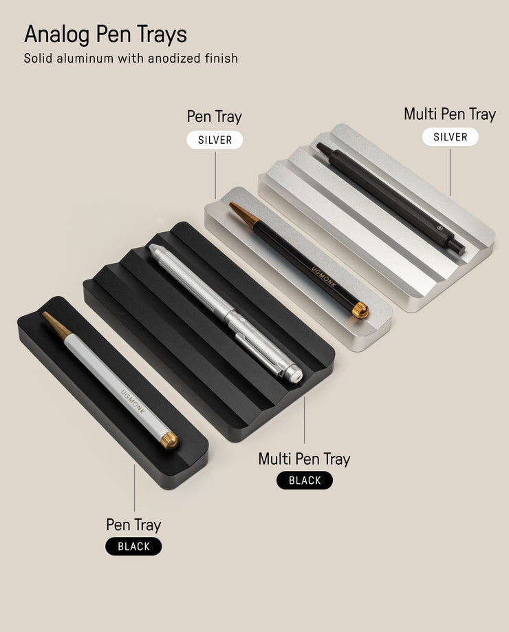 The Analog Multi Pen Tray (Black Aluminum) is shown as a sleek desk organizer. It holds multiple pens and features labels for color and tray type, all displayed on a beige background.