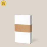 A pack of Analog Dot Grid Cards - Small (1-Pack), neatly stacked 3x5 and wrapped with a brown paper band, displayed against a light beige background.