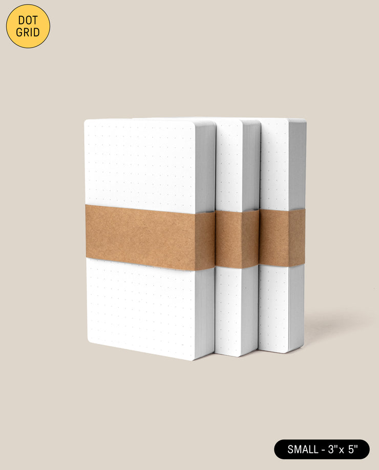 Three Analog Dot Grid Cards - Small (3-Pack) are shown stacked, each with white 3x5 dot grid pages and rounded corners. They’re wrapped in a brown paper band, feature a yellow “DOT GRID” circle, and are labeled “SMALL – 3 x 5” at the bottom.