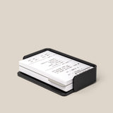 The Analog Capture Kit - Small (Black Aluminum) features a black rectangular card holder, ideal for organizing your Small Dot Grid Cards, containing white index cards with handwritten notes on a light beige surface.
