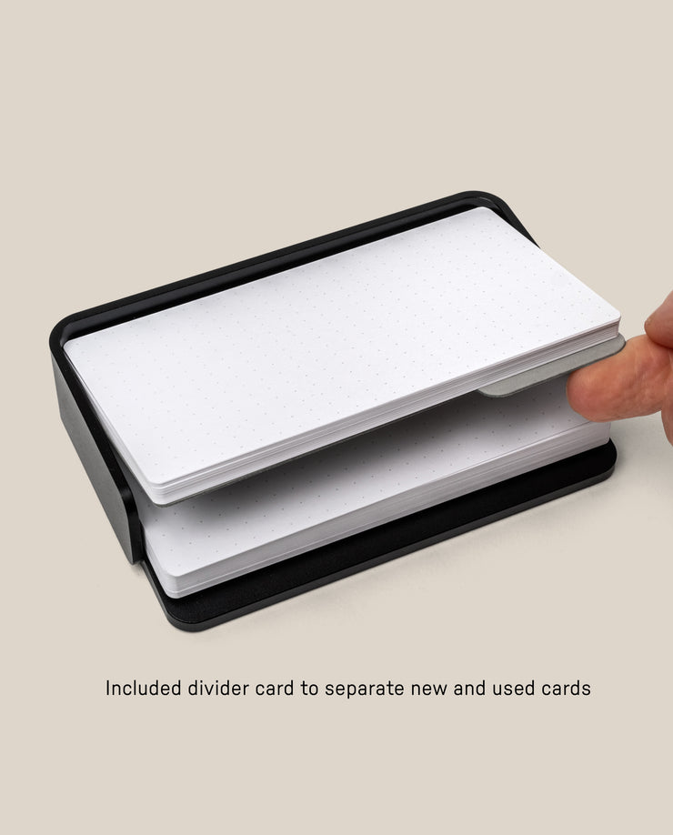 A hand slides a divider card between two stacks of cards in the Analog Capture Kit - Small (Black Aluminum). Text below reads: Included divider card to separate new and used cards.