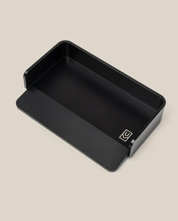 The Analog Capture Kit - Small (Black Aluminum) is a black rectangular aluminum card tray with rounded corners, a low front edge, and a small white geometric logo—ideal for organizing your Small Dot Grid Cards against any backdrop.