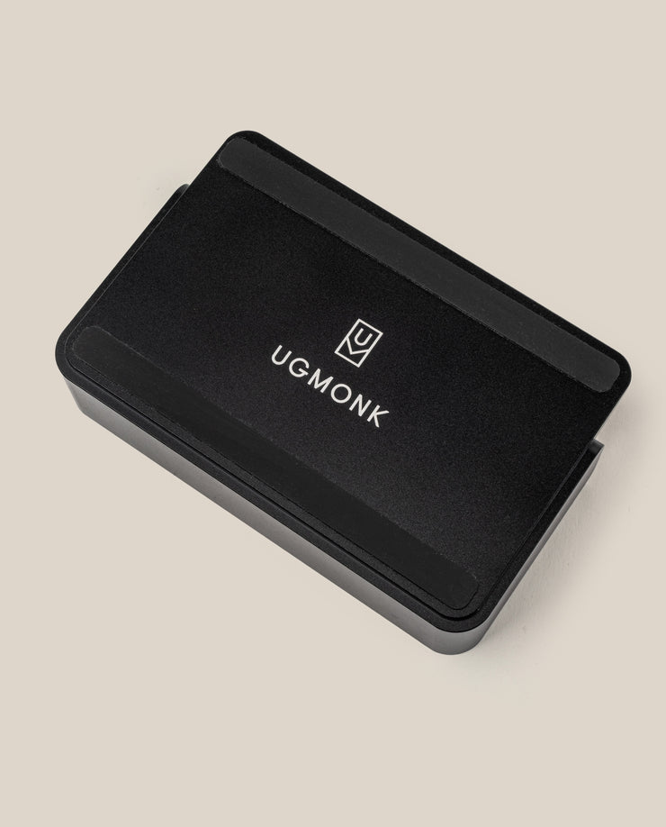 A black rectangular card organizer with rounded edges, featuring the UGMonk logo and name in white, set on a beige background—part of The Complete Analog Collection (Black Aluminum).