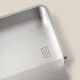 A close-up of the Analog Capture Kit - Small (Silver Aluminum), an aluminum card tray with rounded edges and a small engraved geometric logo, ideal for organizing Small Dot Grid Cards, shown on a beige background.
